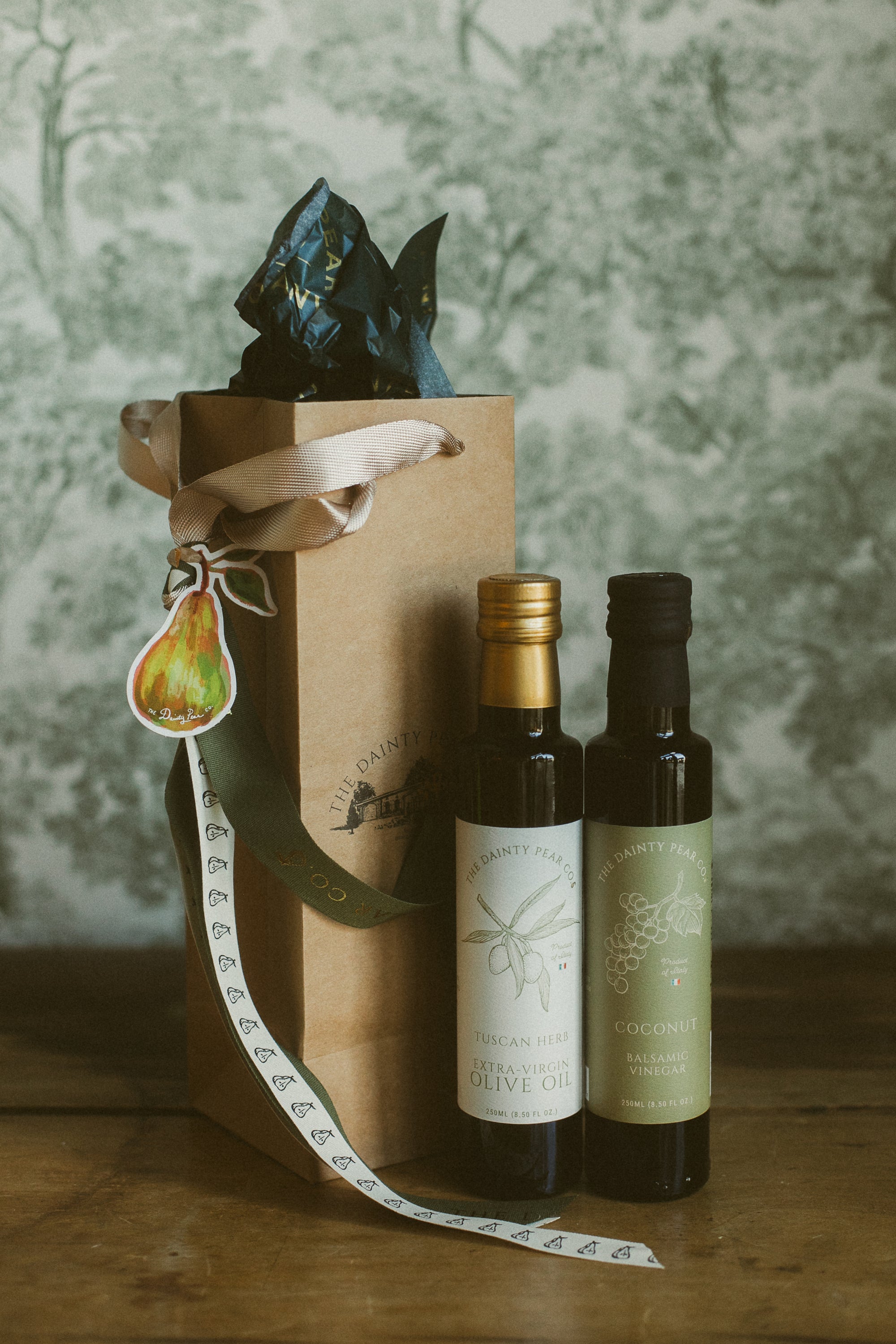 Two bottles of olive oil with a decorative box on a wooden surface.