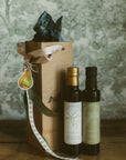 Two bottles of olive oil with a decorative box on a wooden surface.