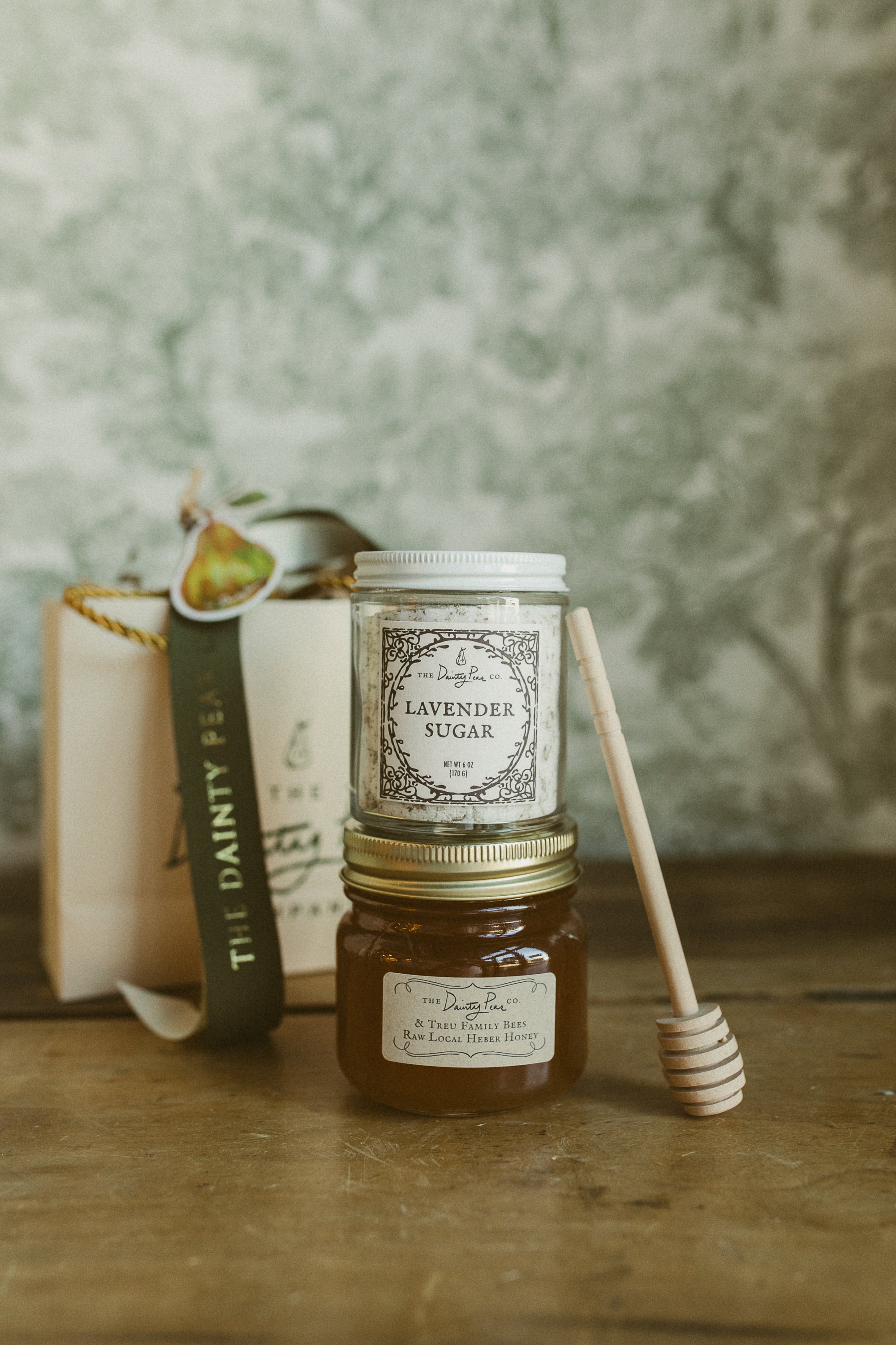 Jar of lavender sugar and honey with a book and spoon on a wooden surface