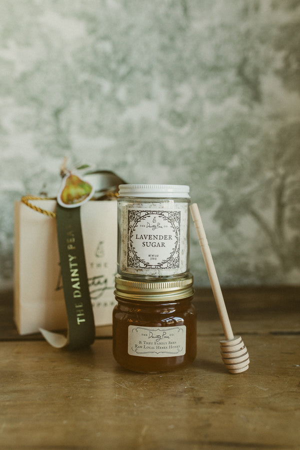 Jar of lavender sugar and honey with a book and spoon on a wooden surface