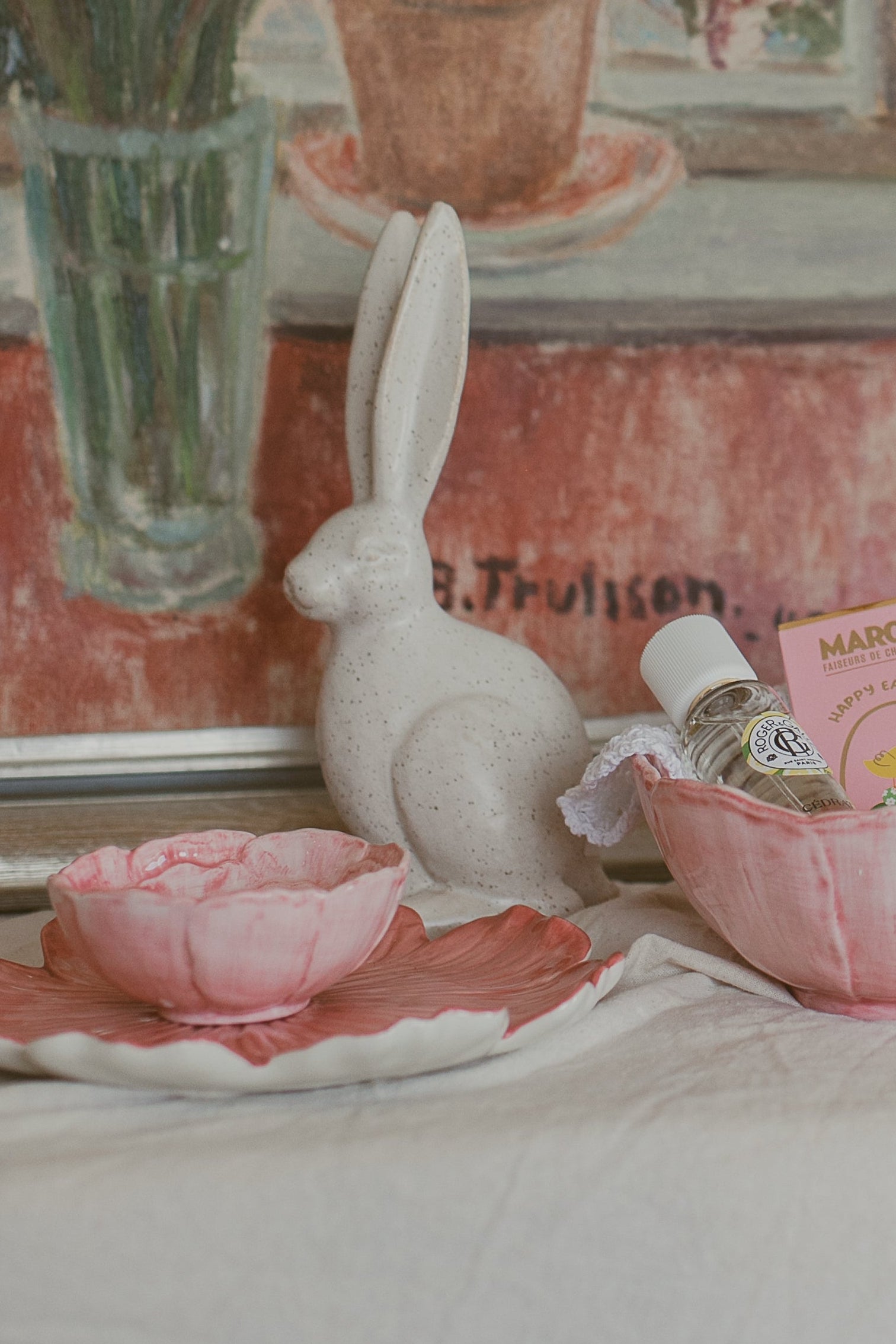 Framed painting of flowers on a table with a lemon and rabbit figurine.