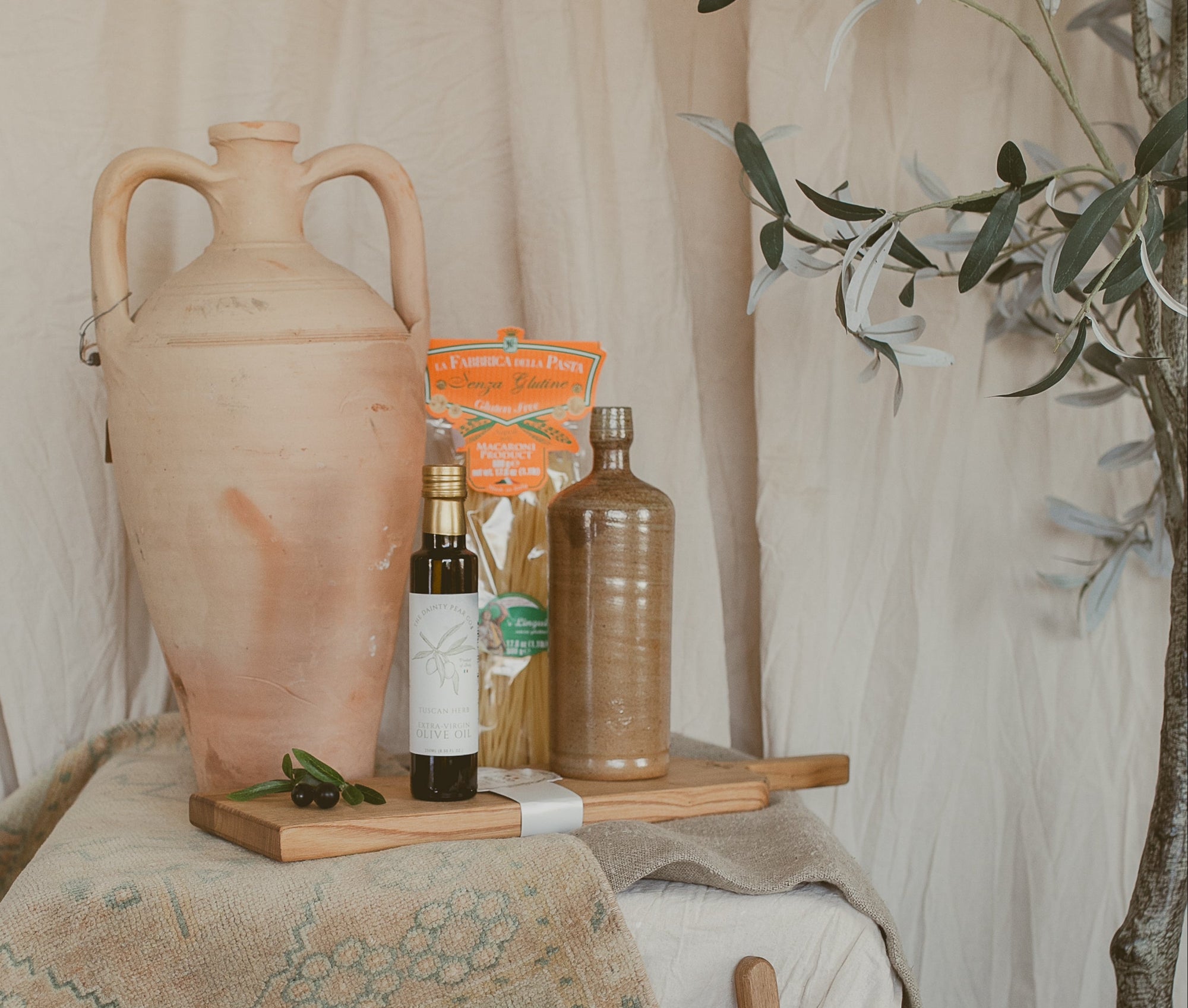 Decorative setting with rustic vases, bottles, and a tree in a softly lit room.