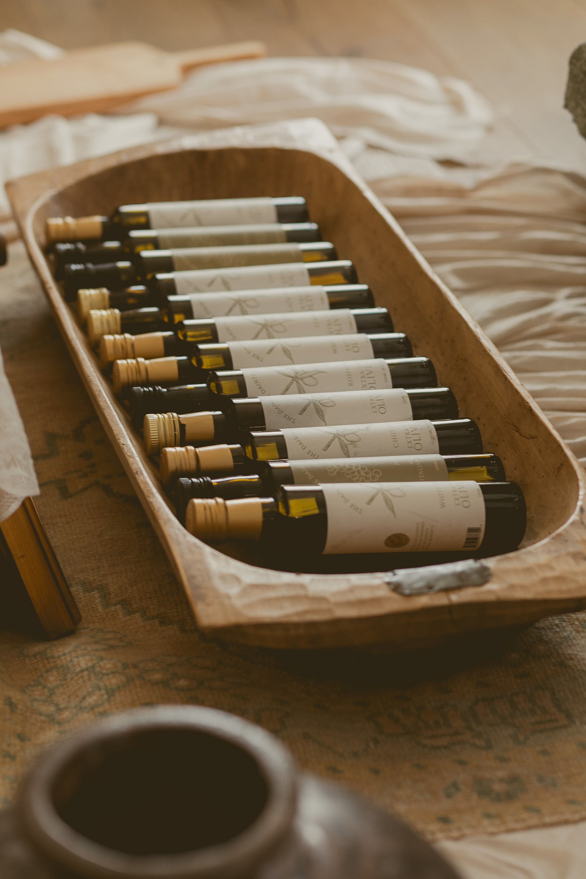 Artisanal olive oils displayed on rustic wooden cutting board with Mediterranean decor at The Dainty Pear Co.
