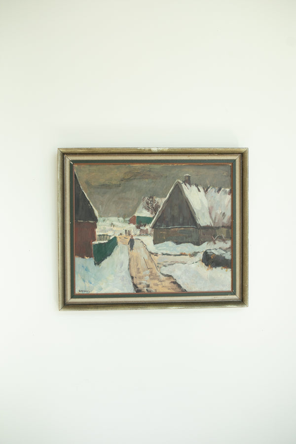 Framed painting of a snowy landscape with buildings on a white wall